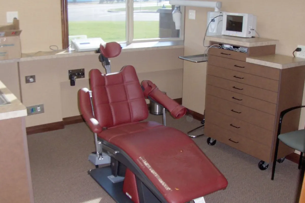 Treatment room with a red chair and wood casework at Central Lakes Oral & Facial Surgery