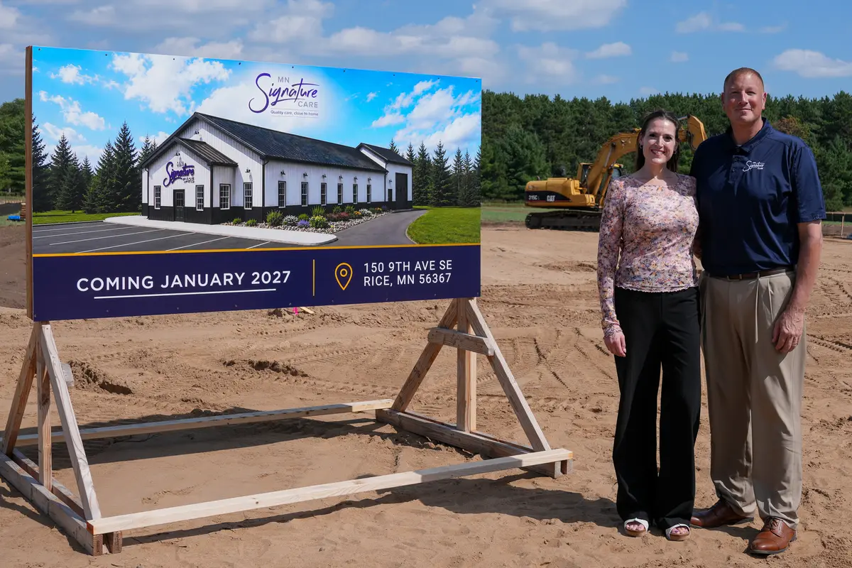 Two guests beside the MN Signature Care headquarters sign